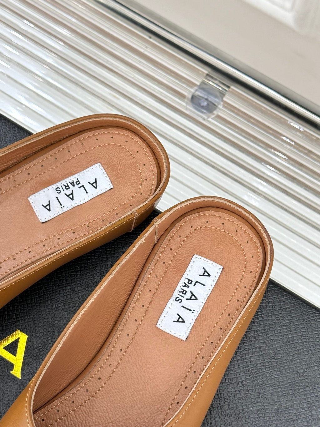 ALAIA FLAT MULE IN BRONZE BROWN LAMBSKIN WITH GOLD HARDWARE