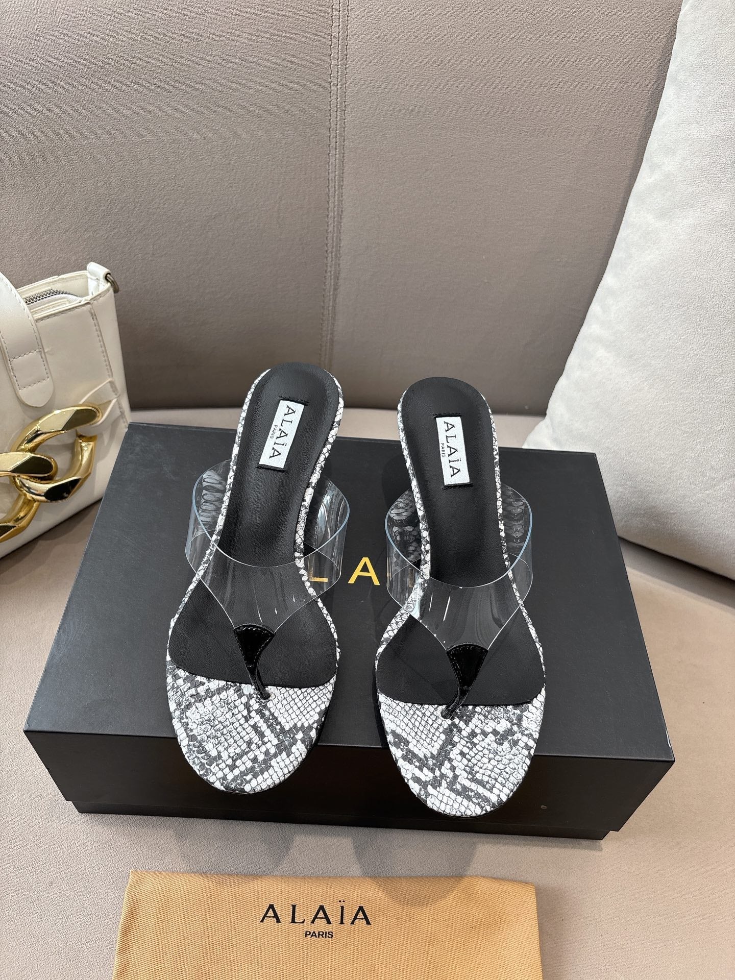 ALAIA HEELED THONG 25S 55 MM IN WHITE AND BLACK LAMBSKIN SNAKE-EMBOSSED WITH CLEAR STRAP