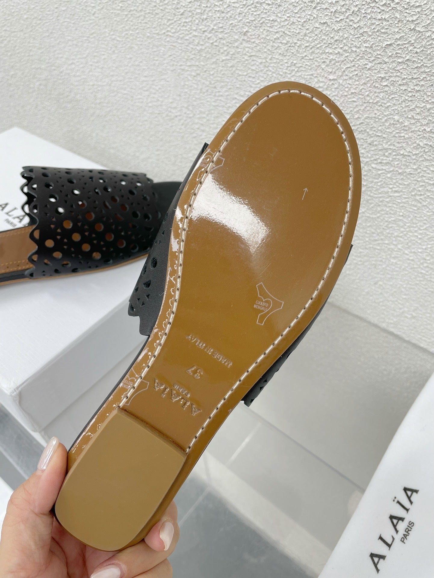 ALAIA VIENNE FLAT MULES IN BLACK LAMBSKIN