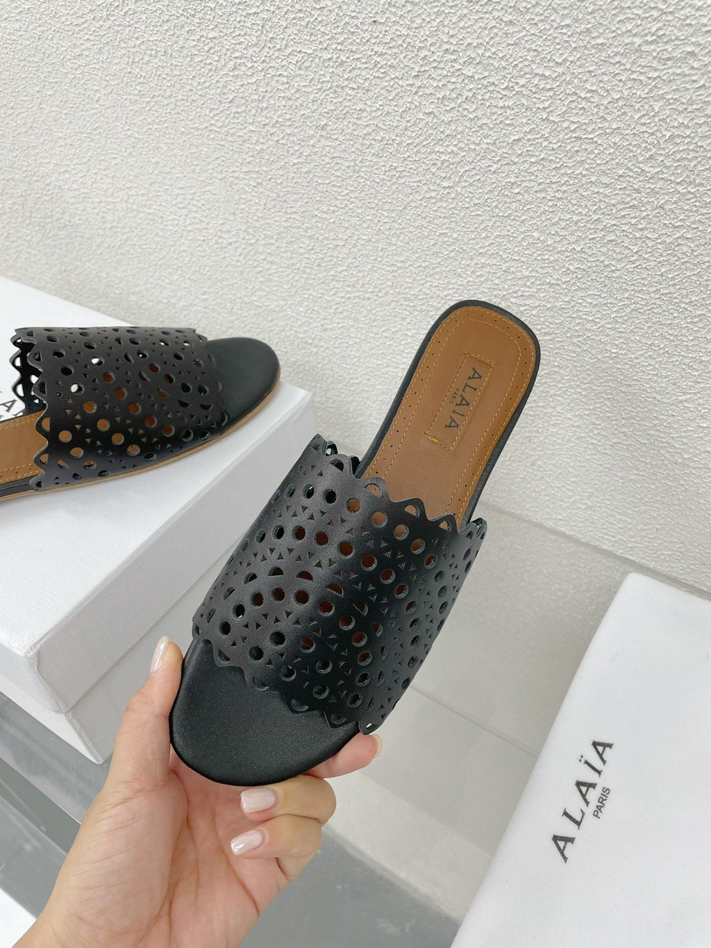ALAIA VIENNE FLAT MULES IN BLACK LAMBSKIN
