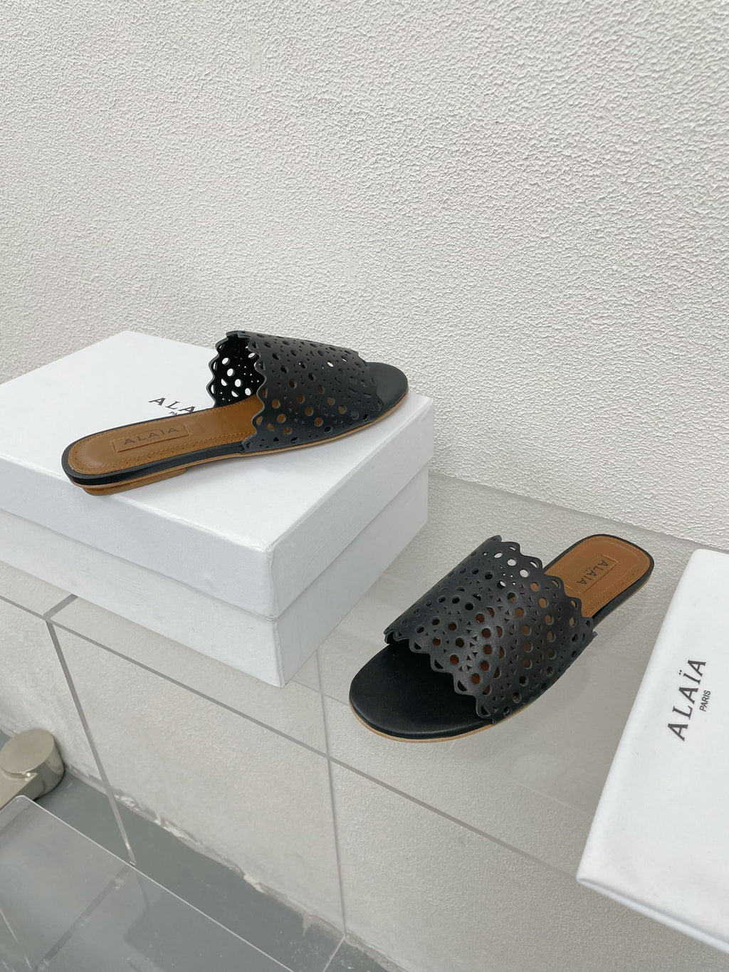 ALAIA VIENNE FLAT MULES IN BLACK LAMBSKIN