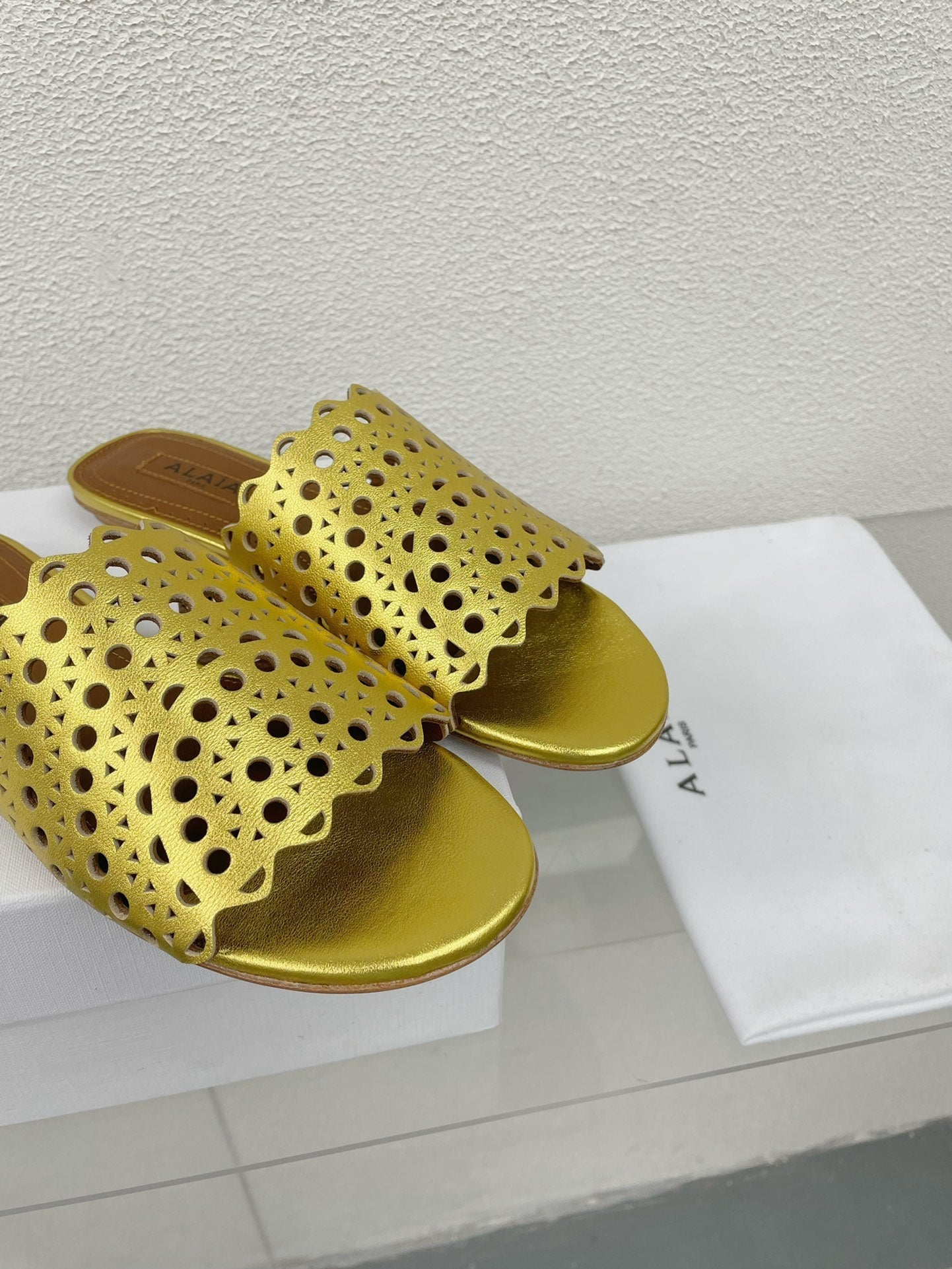 ALAIA VIENNE FLAT MULES IN GOLDEN LAMBSKIN