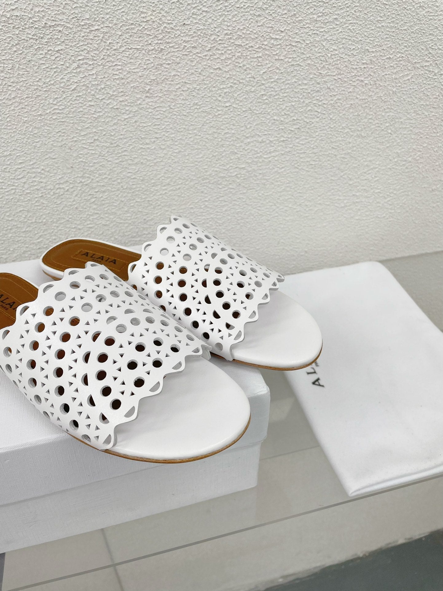 ALAIA VIENNE FLAT MULES IN WHITE LAMBSKIN